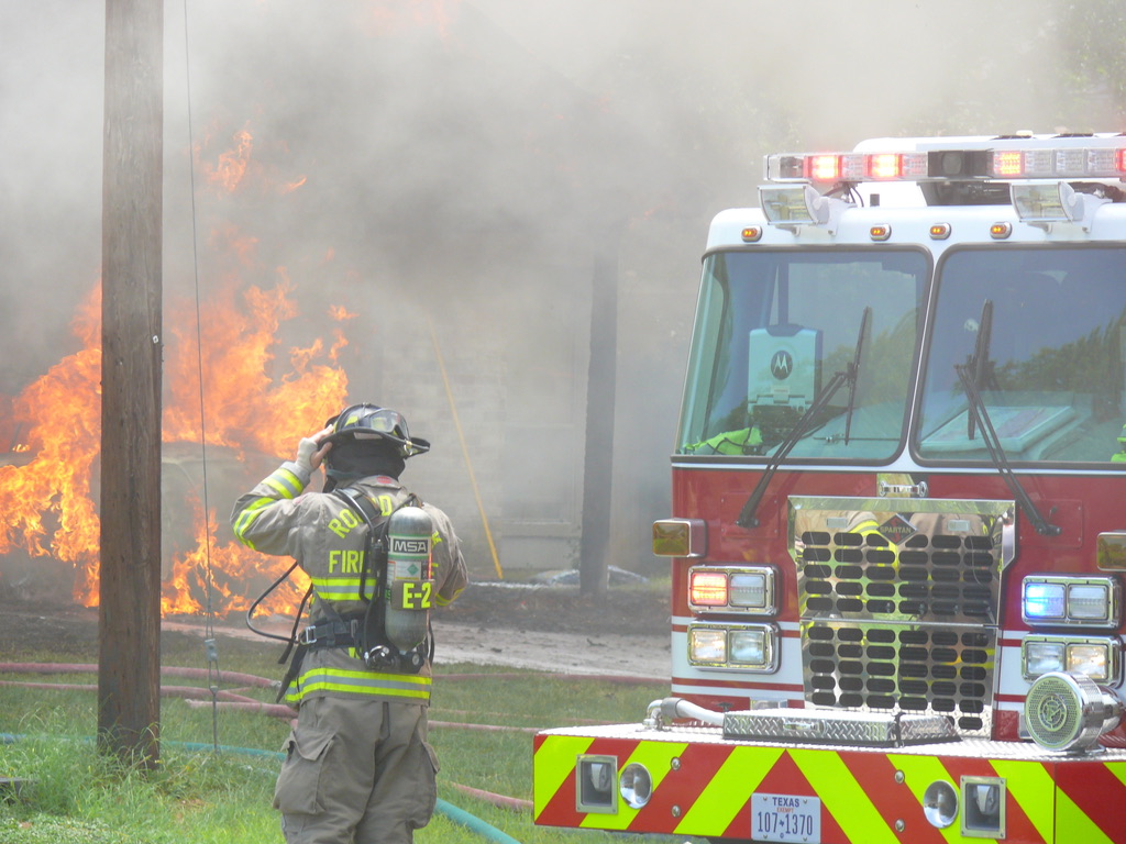 Round Rock firefighter from Engine 2 preparing to 
            attack a car and structure fire on Country Aire Drive.